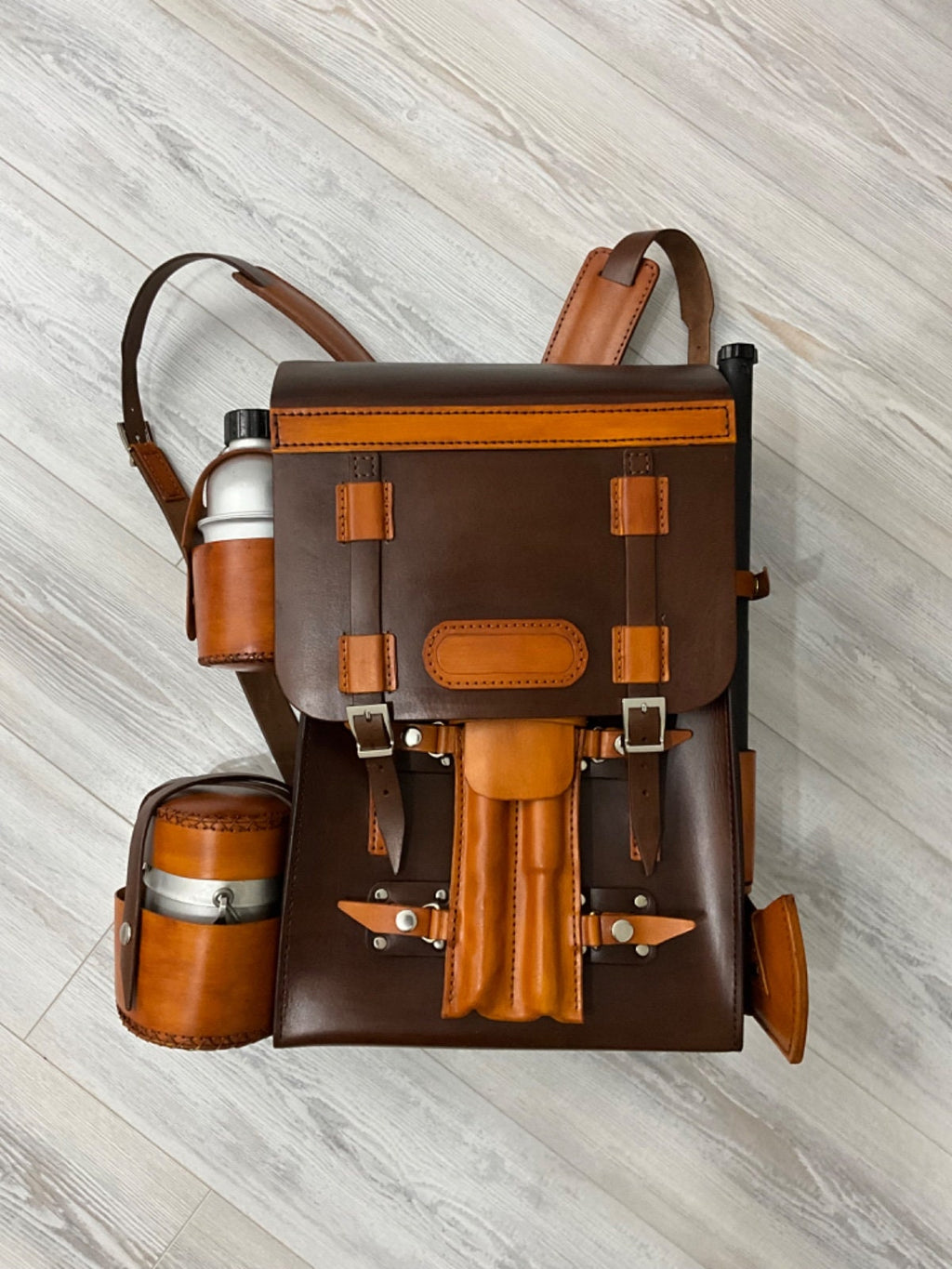 Handmade leather bushcraft bag a bushcraft axe, handmade folding pan, aluminum water carrier, camping pot, bushcraft drill, and bowsaw